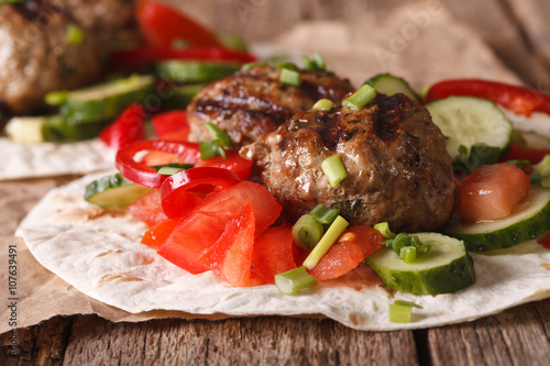 Turkish kofta with fresh vegetables on a flat bread close up. horizontal  