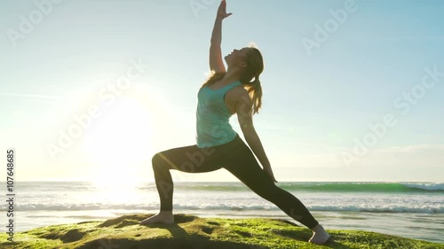 Happy young woman practicing yoga on the beach at sunset. Healthy active lifestyle concept. 4K