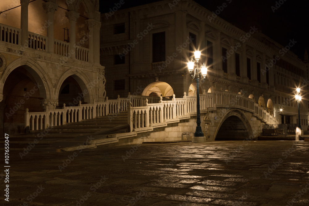 bridge via the Palace channel, a lamp and a wall of Doges Palace at night during a rain, Venice