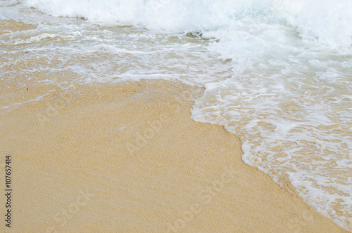 Shore of the beach, where the wave breaks and the foam of the sea is seen on the sand.
