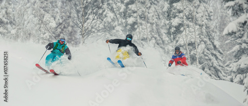 Three skiing friends moving downhill
