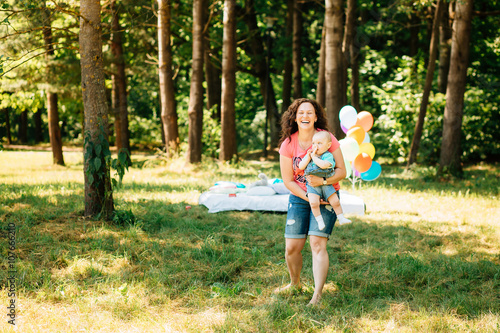 Young mother with little son having fun outdoors at picnic in the park