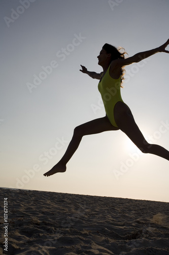 femme le soir en contre jour sur le sable saut en l'air