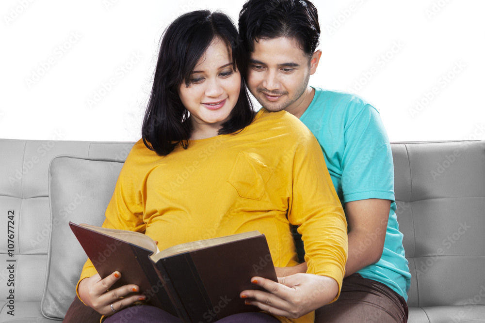 Pregnant woman and husband reading book Pregnant woman and husband reading book