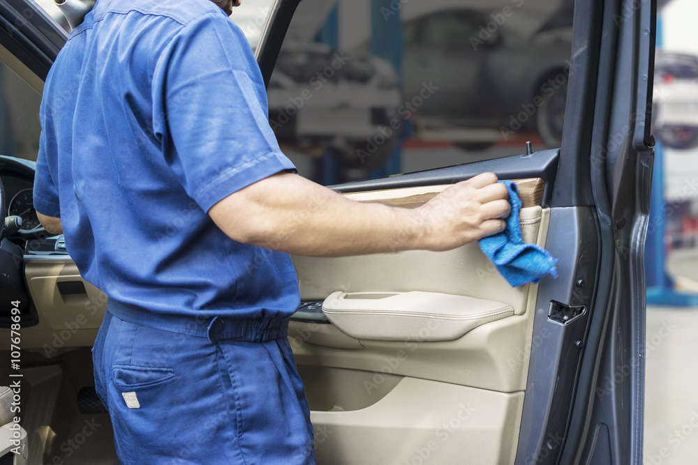 Worker wiping a car door with cloth Worker wiping a car door with cloth