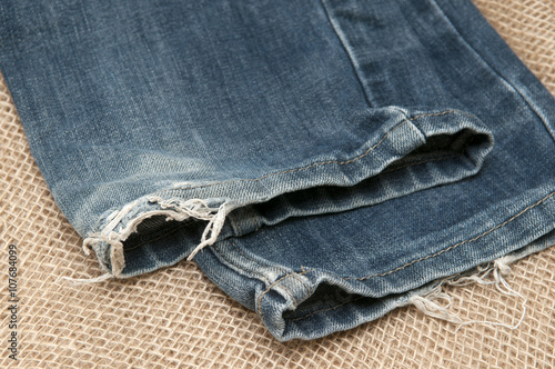 Old torn jeans on a background of burlap.