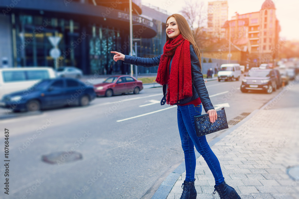 Fashion shot of pretty young woman over city background, wearing red scarf. City lifestyle. Female fashion