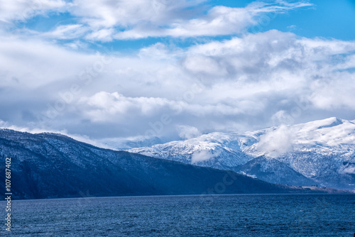 Snow caped mountain range in Norway under a blue cloudy sky