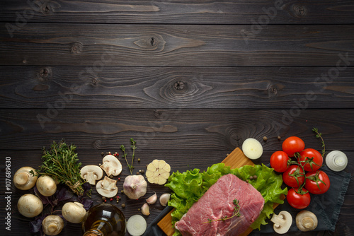 raw meat with ingredients on a wooden background