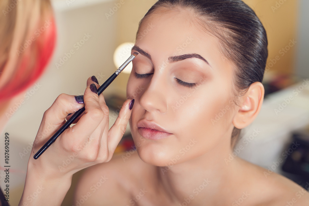 Professional make-up artist preparing model for studio shot