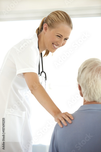 Beautiful young female doctor talking to senior patient