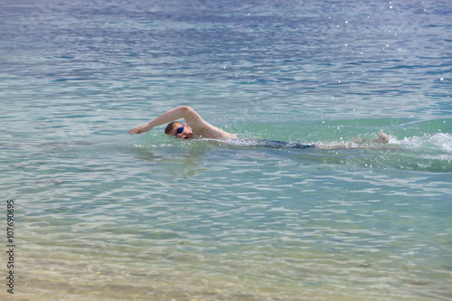 young sporting man swims in the sea
