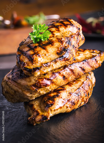 Grilled chicken breast in different variations with cherry tomatoes, .mushrooms, herbs, cut lemon on a wooden board or teflon pan. Traditional cuisine. Grill kitchen.