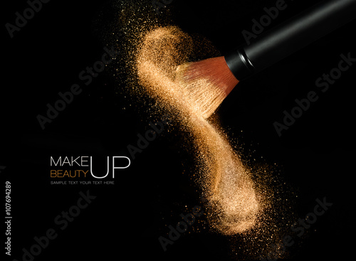 Cosmetics brush with glowing face powder. Dust explosion