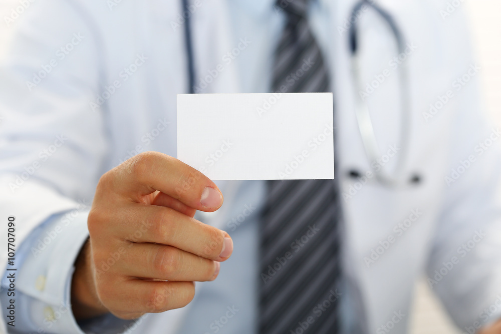Male physician hand holding and giving white blank calling card Male physician hand holding and giving white blank calling card