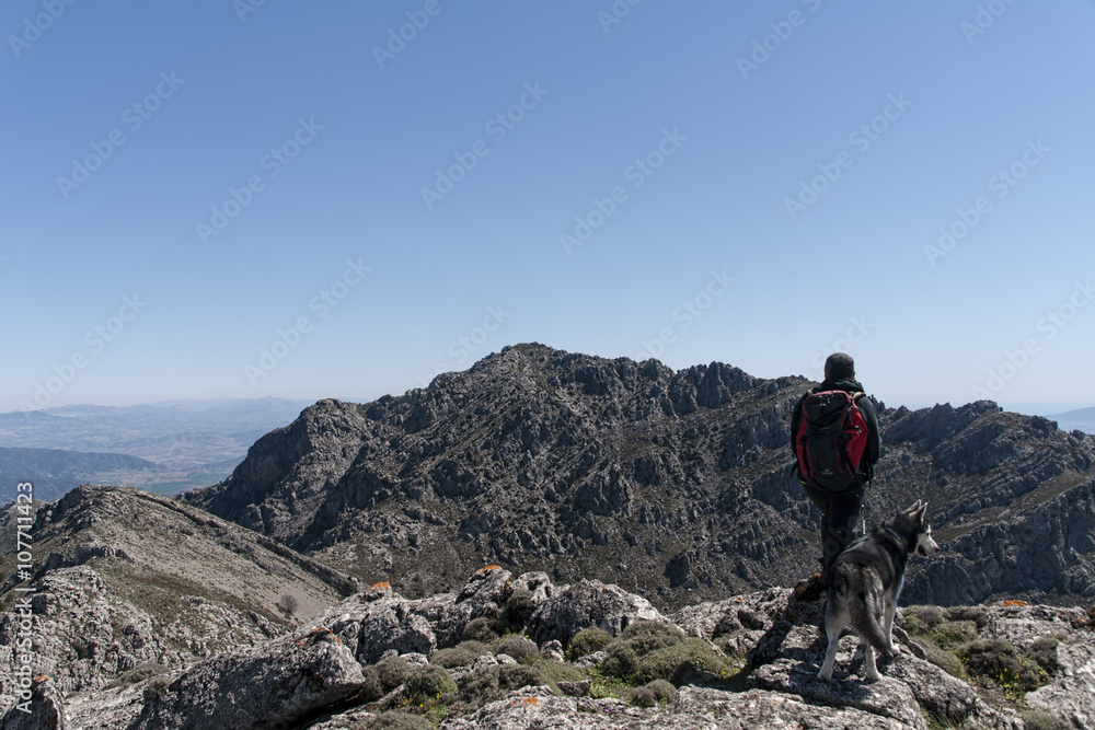 senderista en la cima de la montaña junto a su mascota