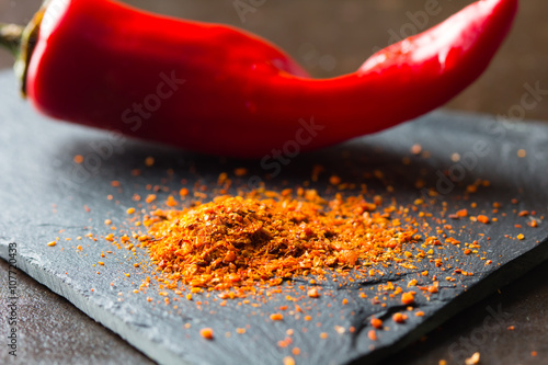 Canvas Print Closeup of dry ground chile on stone board with fresh red  chili on background