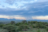 Savanna plain against distance view of mountain against storm cloudy sky background. Serengeti National Park, Tanzania, Africa. 
