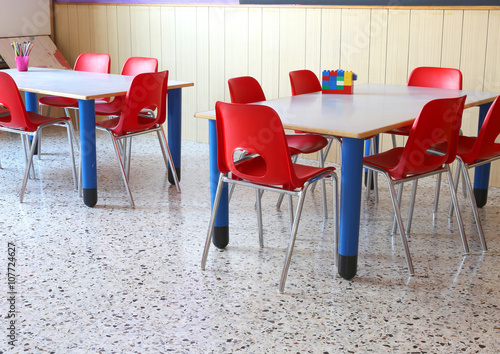 classroom of a kindergarten with red chairs and small school tab