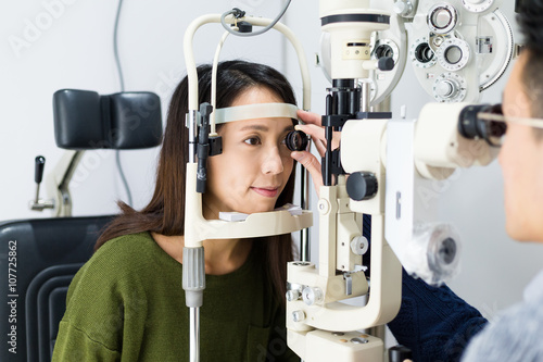 Woman checking vision with tonometer at optical clinic
