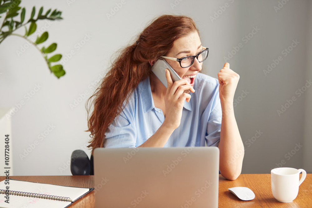 Headshot of a successful businesswoman looking excited talking on cell phone. Portrait female freelancer shouting with excitement and joy. Attractive female manager winning business sitting in office Headshot of a successful businesswoman looking excited talking on cell phone. Portrait female freelancer shouting with excitement and joy. Attractive female manager winning business sitting in office