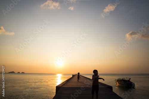 Pier landscape at sunset, people the going on a pier, happy people walking at the sea and observing a decline