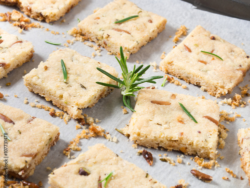 Cookies with rosemary, pignoli and pistachio nuts on baking parchment decorated with rosemary sprigs photo