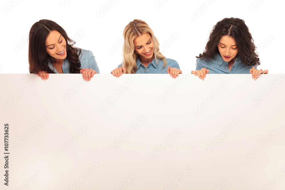 three happy women looking down to big blank board three happy women looking down to big blank board