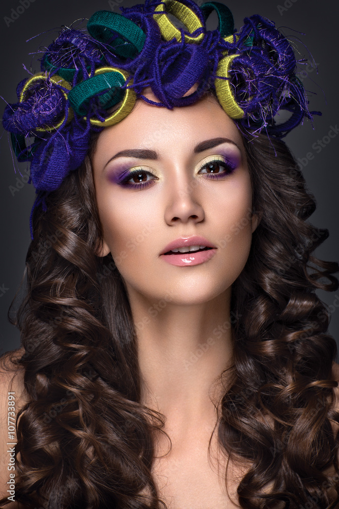 Fototapeta premium Beautiful woman portrait. Young lady posing isolated on dark background. Girl with colorful eyeshadow, nude lips, cotton jewelry on head