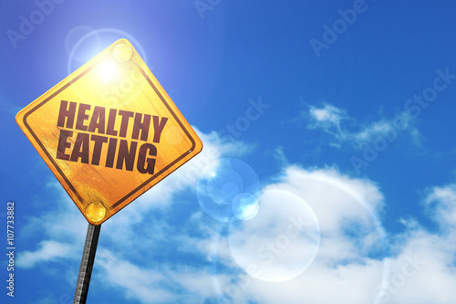 Yellow road sign with a blue sky and white clouds: healthy eatin photo