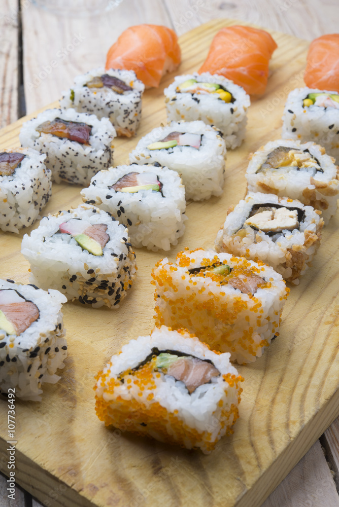 Different Sushi rolls,wasabi and ginger on a plate on wooden bac Different Sushi rolls,wasabi and ginger on a plate on wooden bac