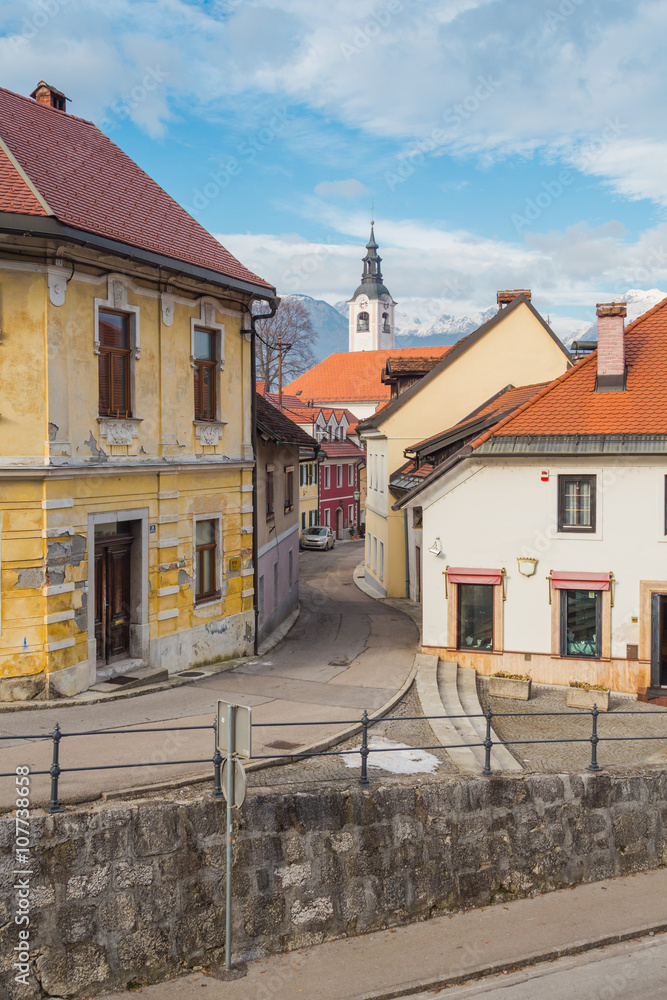 Small European medieval street overlooking the church and mountains on the background.