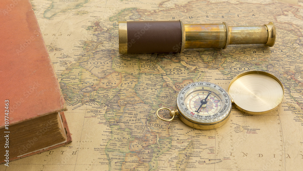 Old book and old spyglass and old compass on vintage map world discovery concept