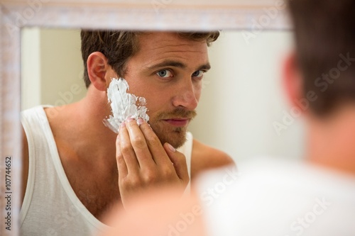 Tableau sur toile Young man applying shaving foam on his face