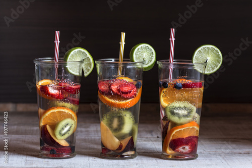 Detox water with fruit in glasses served in wooden tray. Rustic photo