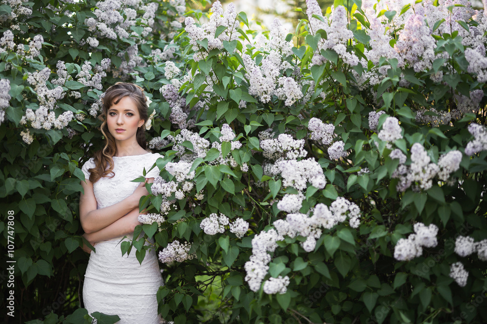 Elegant brunette in white dress in lilac garden Elegant brunette in white dress in lilac garden