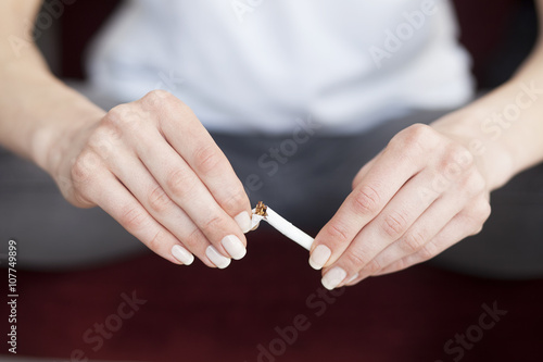 Close up of woman hands with broken cigarette. Stop smoking conc