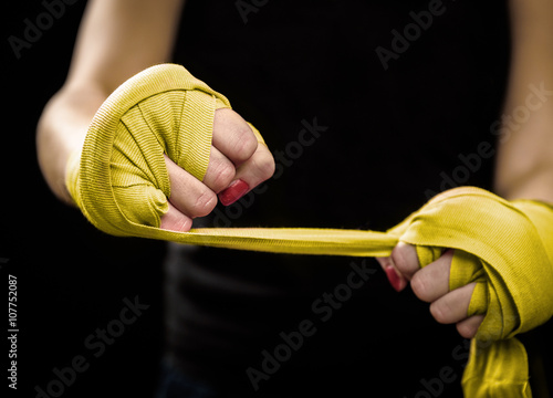 Woman is wrapping hands with yellow boxing wraps photo