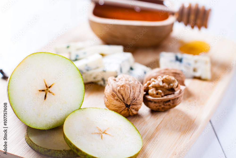 Blue cheese with slices of pear, nuts and honey on bamboo wooden cutting board. Blue cheese with slices of pear, nuts and honey on bamboo wooden cutting board.