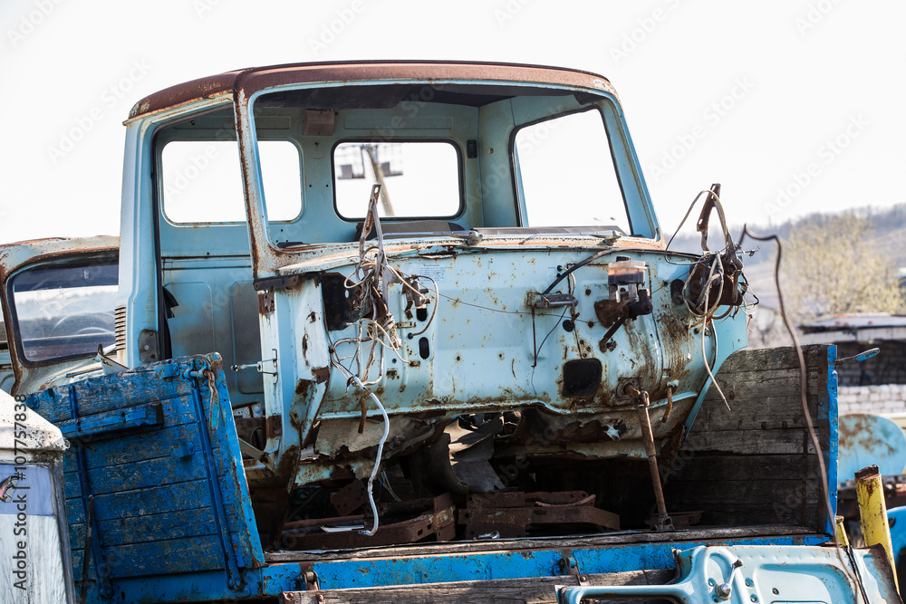 part of the dismantled rusty blue car in the dumps
