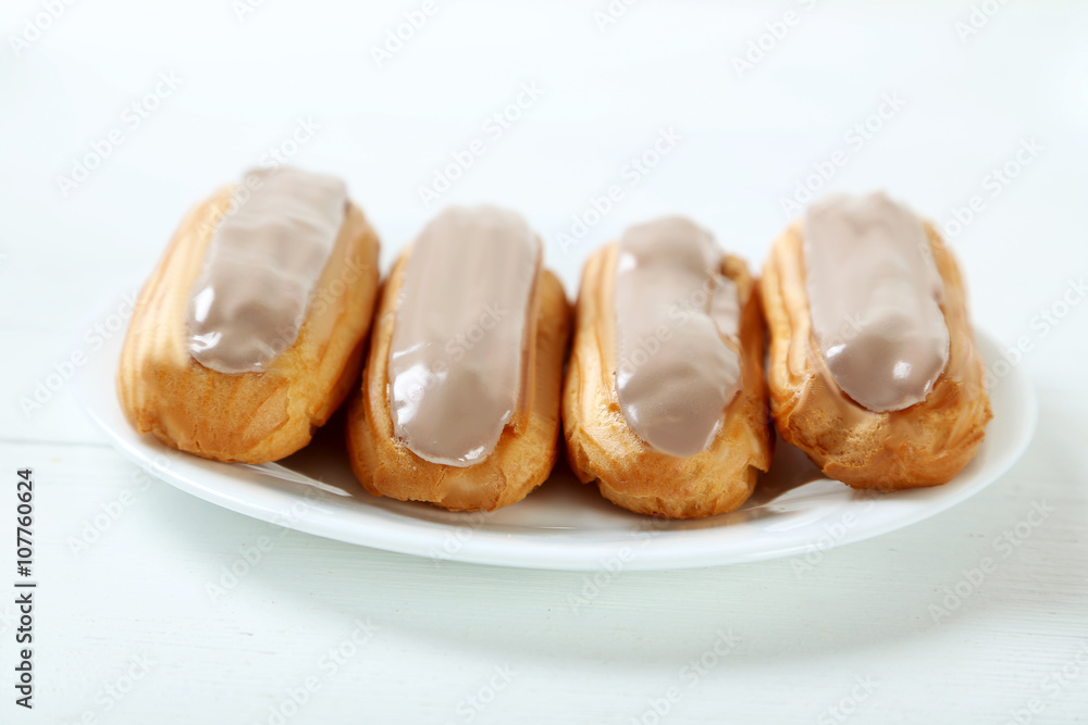 Eclairs with glaze on a white wooden table Eclairs with glaze on a white wooden table