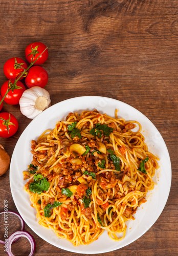 spaghetti with mushroom, vegetables and minced meat in a plate on wooden table