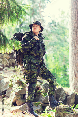 young soldier with backpack in forest