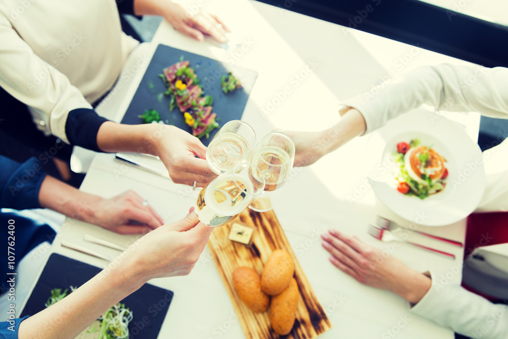 Obraz premium close up of women clinking champagne at restaurant