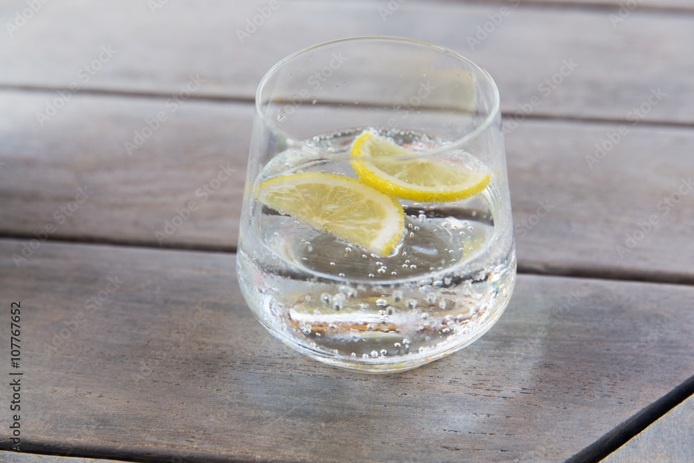 glass of sparkling water with lemon on table glass of sparkling water with lemon on table