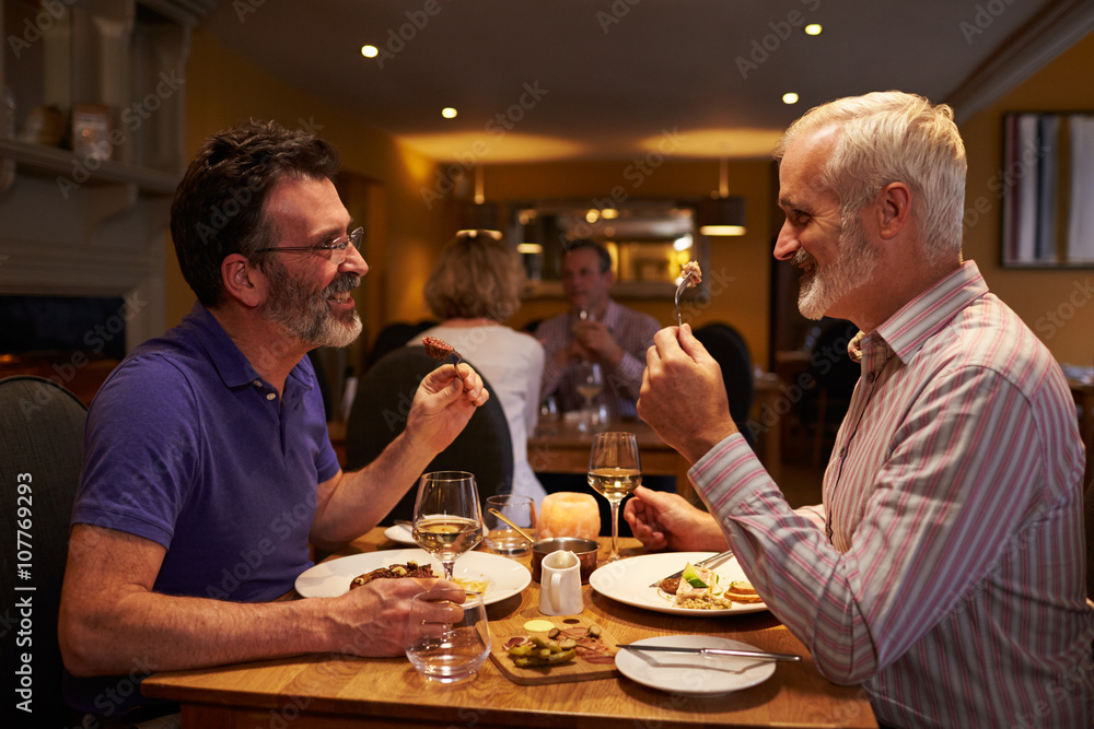 Middle aged male couple eating evening meal in a restaurant Middle aged male couple eating evening meal in a restaurant
