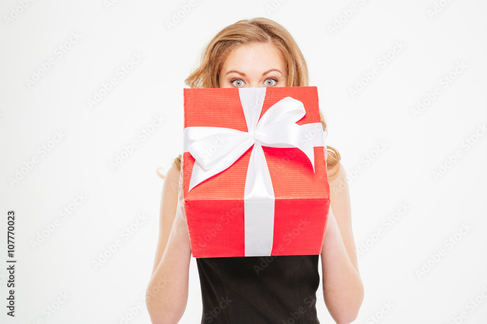 Cute lovely young woman hiding her face behing present box Cute lovely young woman hiding her face behing present box