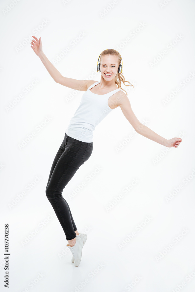 Cheerful woman in yellow headphones listening to music and dancing