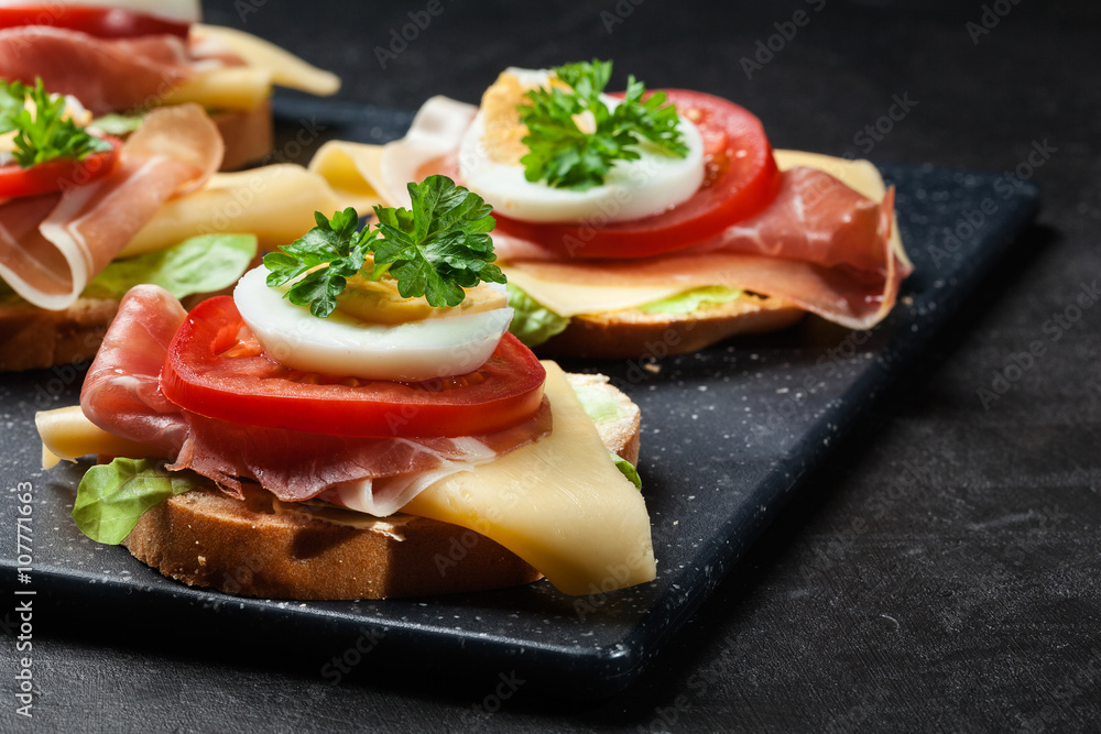 Delicious sandwich with prosciutto ham, cheese, tomato and egg