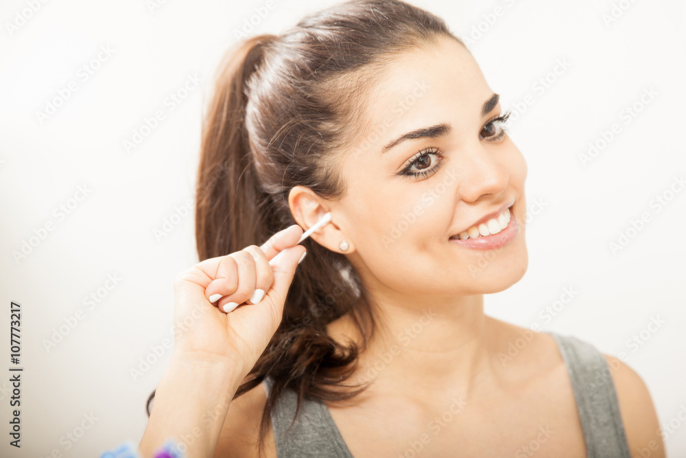 Pretty girl cleaning her ears in a bathroom Pretty girl cleaning her ears in a bathroom